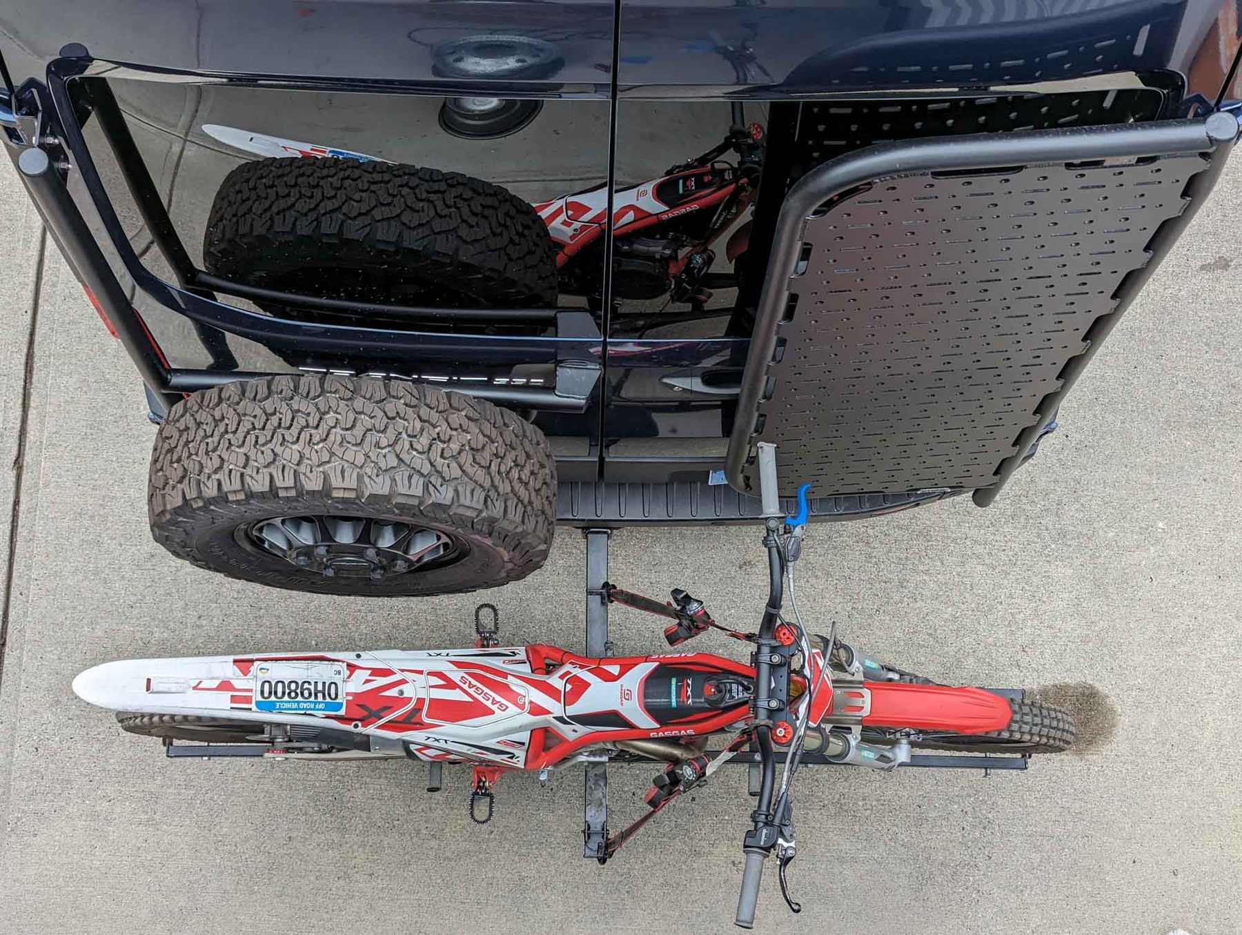 Overhead view of the back of the van: a spare wheel and a cargo platform mounted on the rear doors, and a trials motorcycle carried on a hitch rack below them
