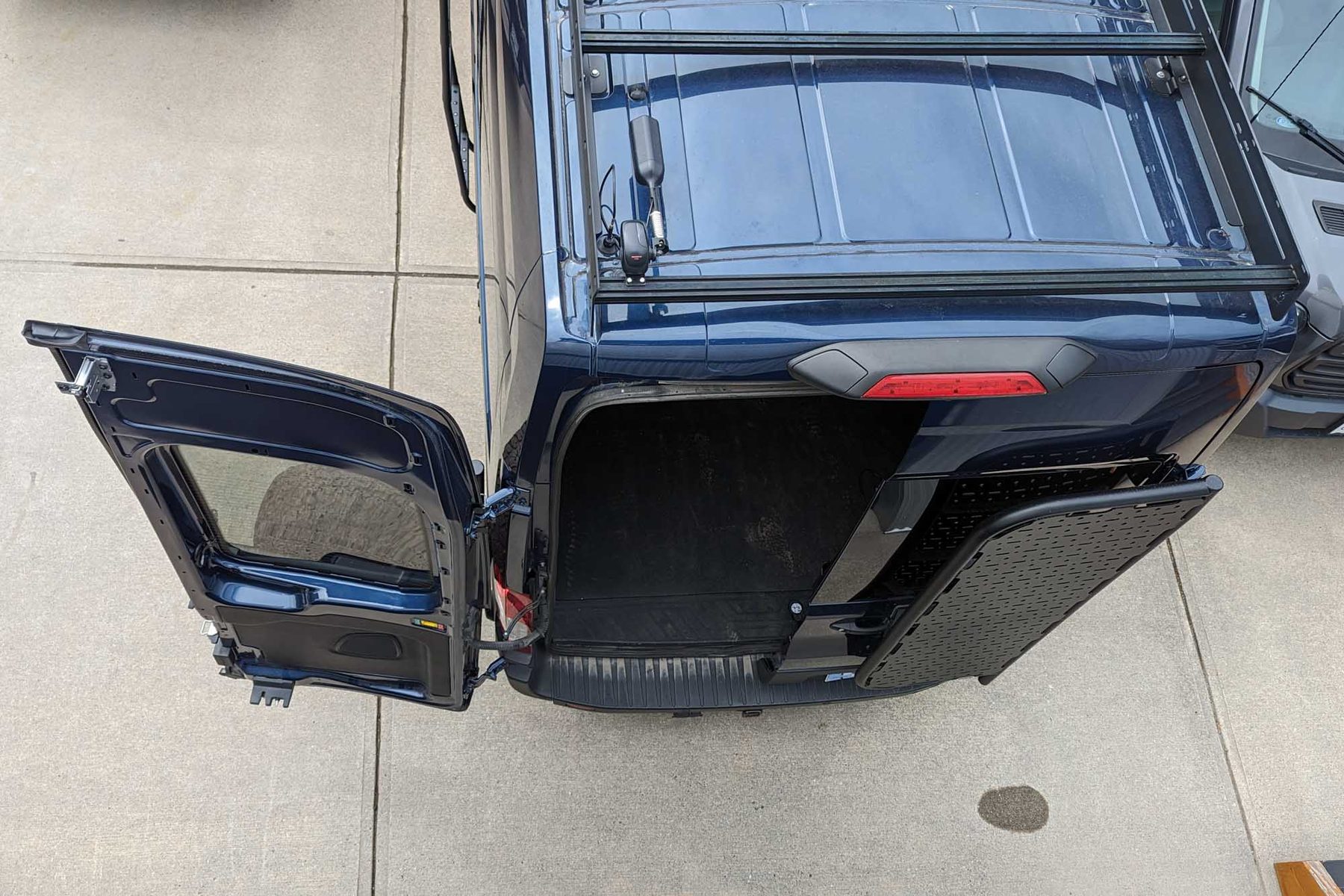 The van's rear doors open on a driveway, one door swinging short of its full travel with the spare wheel carrier mounted on it