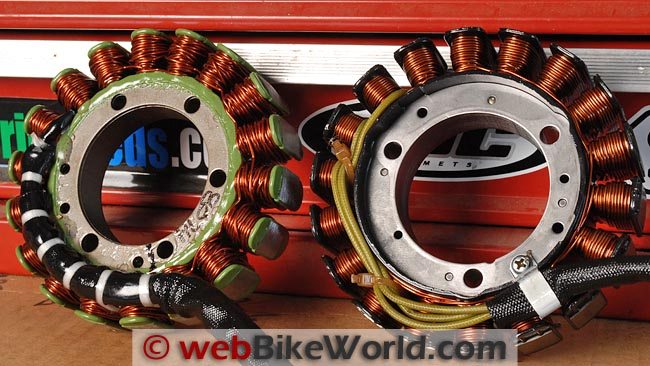Two motorcycle stators side by side on a red toolbox, rings of copper windings, the aftermarket one on the left with thicker green epoxy